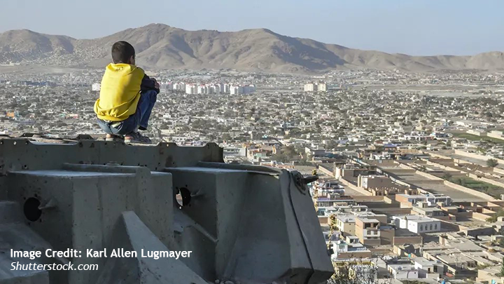Boy sitting in front of a view over Kabul