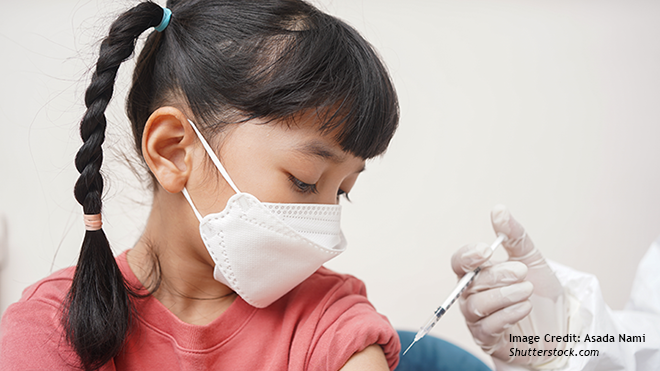 A girl wearing a facemask gets vaccinated