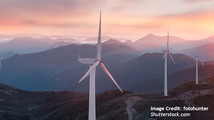 A landscape with mountains and wind turbines and the sunset in the background